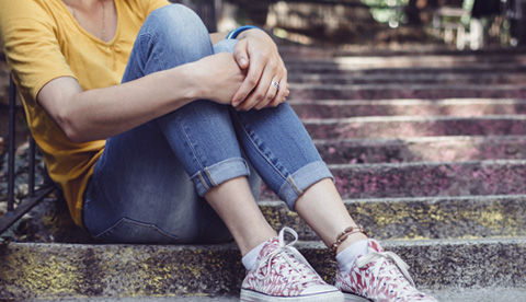 Person som sitter ner och håller om sina knän